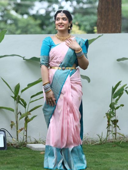 Lalitha radiates elegance in this traditional silk saree, featuring a striking contrast of pretty pink and blue.