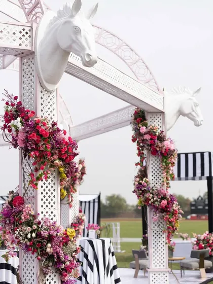 White trellises decorated with horse-head motifs and cascading floral arrangements. These structures added a touch of equestrian elegance to the polo-themed event.