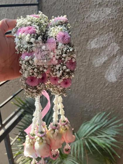 A close-up of a floral kaliree made with pink chrysanthemums, baby's breath, and hanging rosebuds. This shows the dense, textured top part of the accessory.