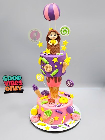 A sweet explosion of fun with this Candyland anti-gravity cake. It features an ice cream cone supporting a floating cake tier, topped with a hot air balloon and surrounded by fondant candies.