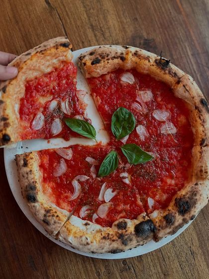 Taking the first slice of our Marinara pizza. It's a moment of pure anticipation.