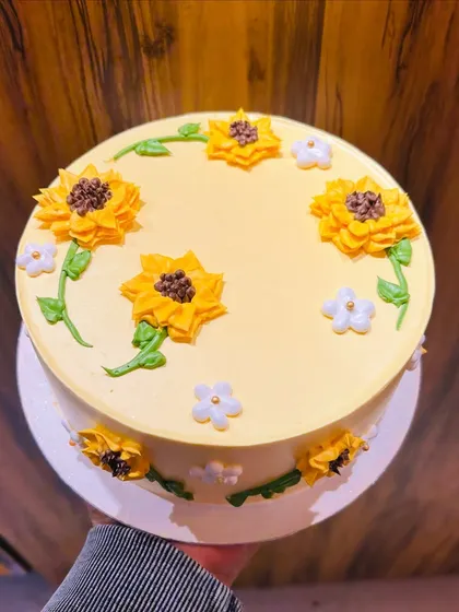 A top-down view of the sunflower cake, held to show the beautiful arrangement of the flowers.