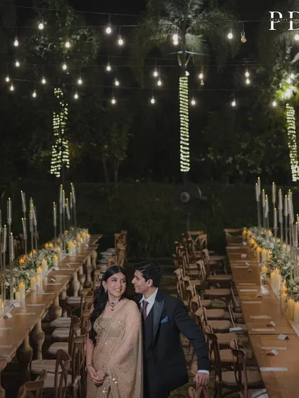 The couple enjoying a quiet moment amidst their beautiful reception setup. The warm glow of the lights creates a romantic and intimate ambiance.