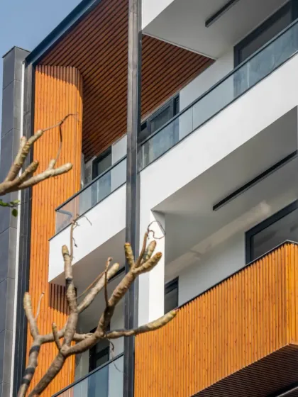 A sneak peek of a new facade, focusing on the clean lines of the wood-finish panels against the white balconies. This detail shot highlights the modern and warm aesthetic of the project.
