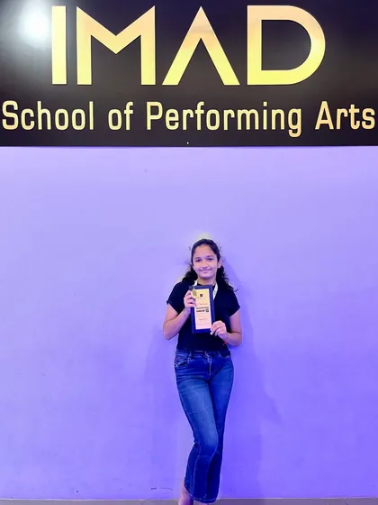 Celebrating a student's individual achievement at our studio. We make sure to recognize personal milestones and hard work in front of the iconic IMAD logo.