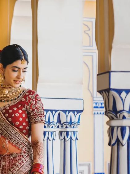 A candid moment of the bride at a royal palace venue. The natural light and architectural details frame her beautifully, creating a portrait that is both elegant and relaxed.