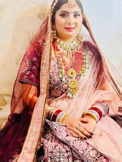 A beautiful bride in a soft pink and maroon lehenga. The multi-layered necklaces and detailed nath complete this traditional and elegant bridal ensemble.