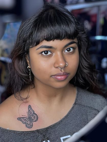 A delicate, fine-line butterfly tattoo on the collarbone. This is a popular choice for a simple yet beautiful piece.