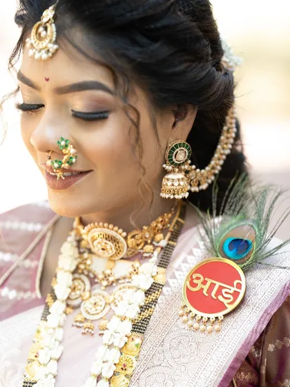 A close-up portrait highlighting the floral 'Aai' brooch with a peacock feather, part of a custom baby shower jewellery set.