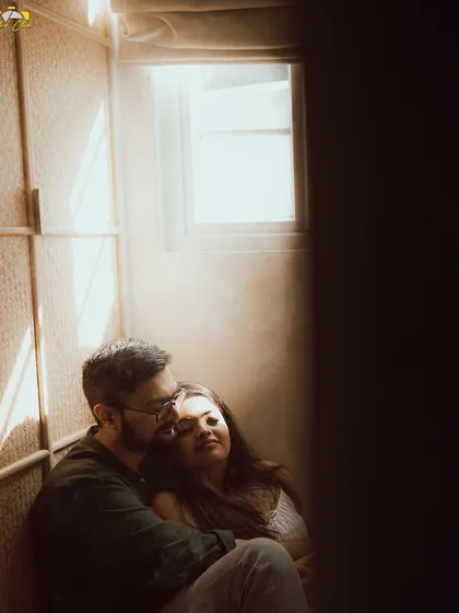 An intimate and moody shot of a couple in a sunlit corner, the light creating a beautiful, hazy effect.