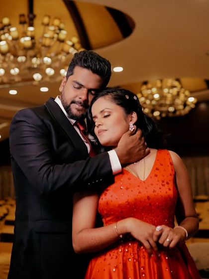 An intimate portrait of a couple in a grand, empty banquet hall. The warm lighting and elegant chandeliers add a touch of glamour and romance.