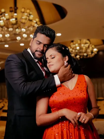 An intimate portrait of a couple in a grand, empty banquet hall. The warm lighting and elegant chandeliers add a touch of glamour and romance.