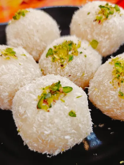 These are our Nariyal Laddoos, or coconut laddoos. Made with fresh coconut and condensed milk, they are soft, chewy, and garnished with pistachios for a delightful and light sweet treat.