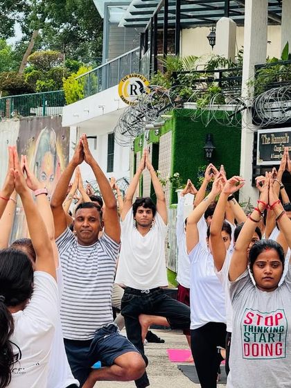 Students reach for the sky in Vrikshasana (Tree Pose) during an outdoor session. Balancing on uneven ground adds a new challenge and deepens focus.