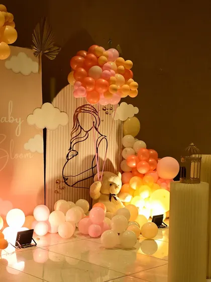 A detailed view of the 'Baby in Bloom' backdrop, featuring a line-art illustration of a mother-to-be, cloud cutouts, and a teddy bear holding a balloon bouquet.