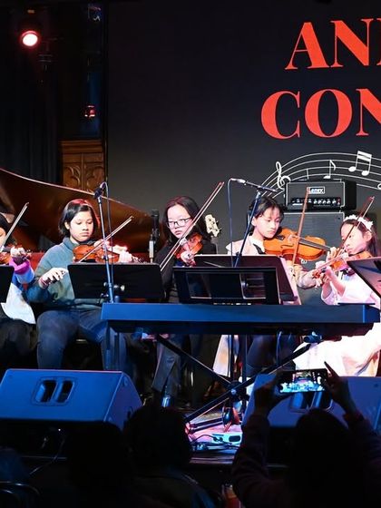 A wider view of our talented Violin Ensemble on stage. We offer comprehensive violin lessons that take students from learning basic notes to performing complex pieces as a coordinated group.