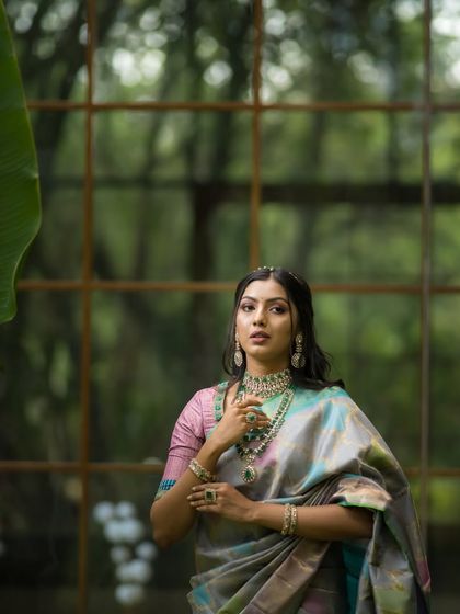 The moody lighting and natural background create a dramatic effect, highlighting the unique colors of the saree.