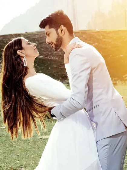 A sun-drenched, romantic photo of a couple in a beautiful meadow in Kashmir. The golden flare adds a magical, dreamy quality to this destination portrait.
