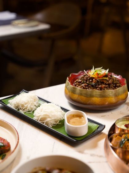 A beautifully plated Kodava dish featuring string hoppers (noolputtu) and a rich, dark curry. This dish is a perfect example of the unique textures and flavors of Coorg's culinary traditions.