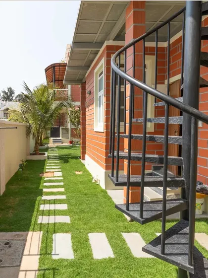 An external spiral staircase offers a space-efficient and visually interesting way to connect different levels of the home, set against the backdrop of the garden.