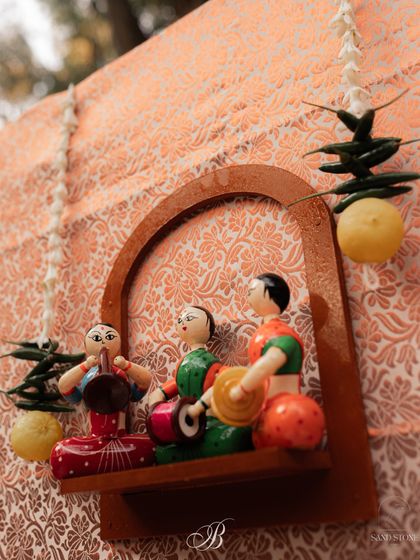 A close-up of the DIY wooden shelf on the band backdrop, featuring a scene of Channapatna musicians. We even added a traditional 'nimbu mirchi' string to ward off the evil eye with style.