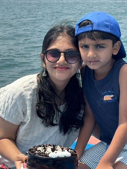 A sweet mother-son moment celebrating a birthday with cake on a boat in the middle of the sea.