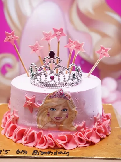 The cake is the centerpiece of the party, and I make sure it matches the theme perfectly. This Barbie-themed cake features a beautiful tiara topper and edible character art, coordinating with the overall pink and princess decor.