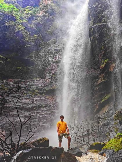 A trekker stands before a tall, majestic waterfall in Uttara Kannada that flows year-round but shows its true power in the monsoon.