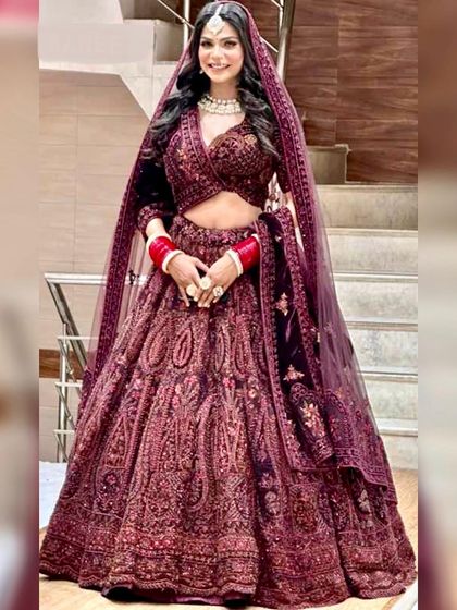 A full-length view of a gorgeous deep wine-colored velvet lehenga. The rich fabric and detailed embroidery make it a luxurious choice for a winter wedding.