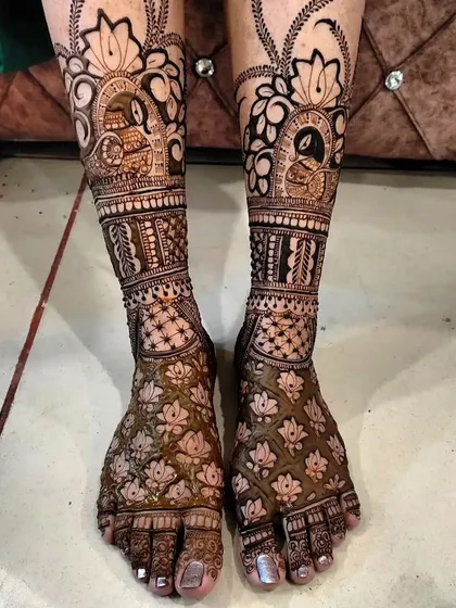 A stunning example of foot mehendi, with lotus flowers and peacock figures. The design covers the entire foot and ankle, creating a rich and full look.