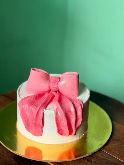 This cake shows my love for clean, minimalist designs. The highlight is a large, handcrafted pink bow, made entirely from chocolate, creating a simple yet stunning centerpiece for any occasion.