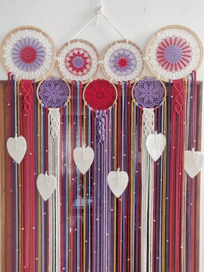 A unique macrame curtain customized for one of our clients. The combination of a dreamcatcher header, colorful strands, and macrame leaves creates a stunning and artistic doorway.