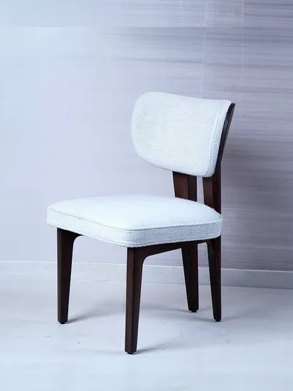 A demonstration of classic elegance, this dining or side chair features a dark wood frame that contrasts beautifully with its light, textured upholstery. The gently curved backrest and cushioned seat provide comfort while maintaining a refined and timeless silhouette.