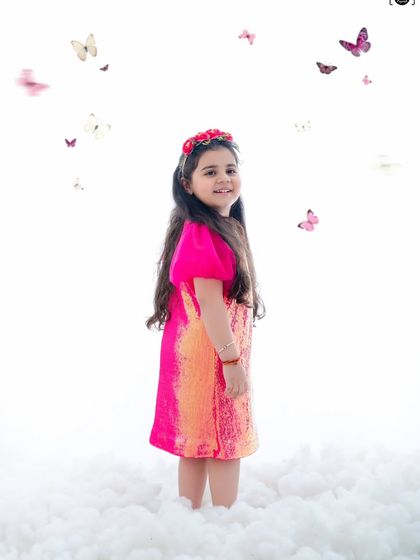 In a world of white whispers and butterfly wings, she blooms in pink magic. A dreamy, ethereal portrait.