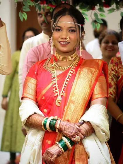 A full-length shot of the bride in her red Nauvari, looking confident and beautiful. The saree is draped to flatter her figure and allow for easy movement.