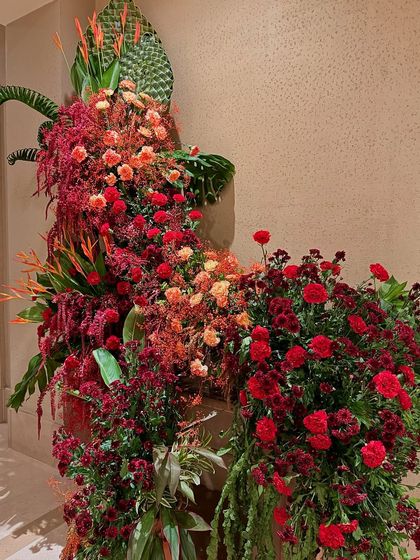 A close-up on the river of red carnations that flows down the arrangement, creating a sense of movement and abundance.