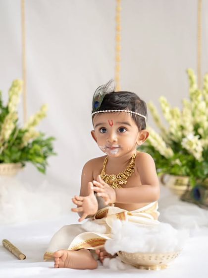 Another little Krishna, caught in the act with a bowl of butter. The details in this setup, from the flowers to the props, are all carefully chosen.