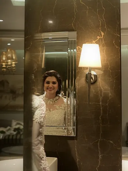 A happy bride looking in the mirror. Her smile shows her confidence and joy, and her makeup is fresh and radiant.