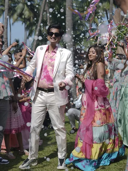 The groom leads the way in a high-energy carnival entrance. The colorful outfits and bubble-filled air perfectly capture the fun and celebratory spirit of the event.