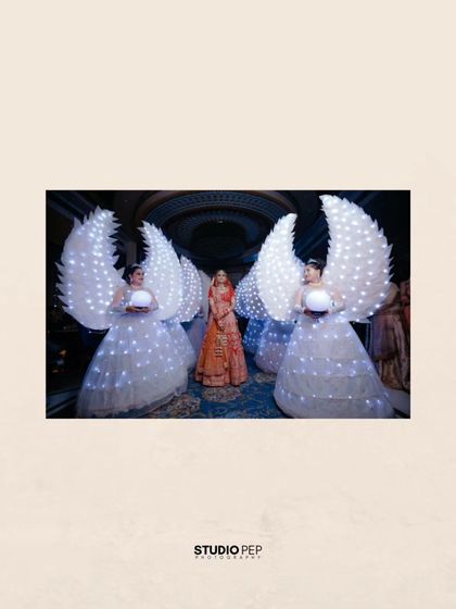 The bride, Vaishali, makes a grand entrance, flanked by performers in illuminated angel wing costumes, creating a truly spectacular moment.