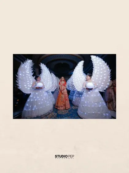 The bride, Vaishali, makes a grand entrance, flanked by performers in illuminated angel wing costumes, creating a truly spectacular moment.