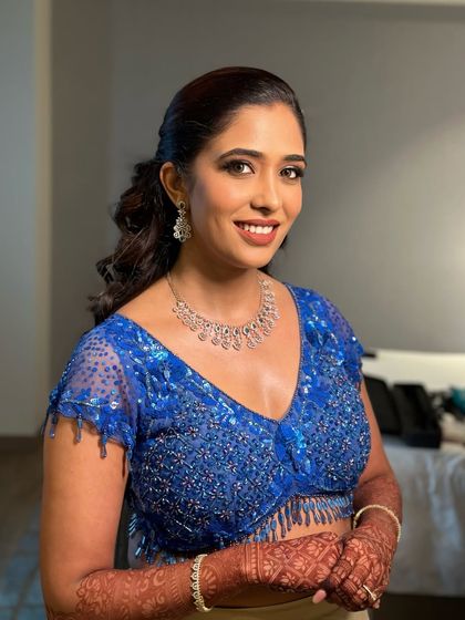 A radiant smile completes any look. Here, her dewy makeup, defined eyes, and a soft pink lip colour harmonize beautifully with her royal blue embellished top and diamond jewellery.