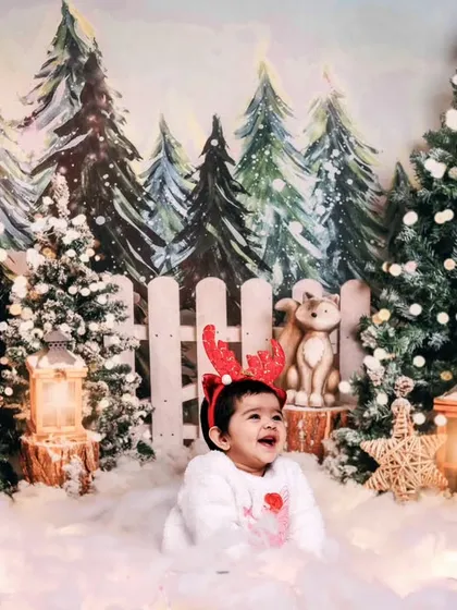 A baby enjoying our snowy forest Christmas theme, complete with reindeer antlers and a happy laugh.
