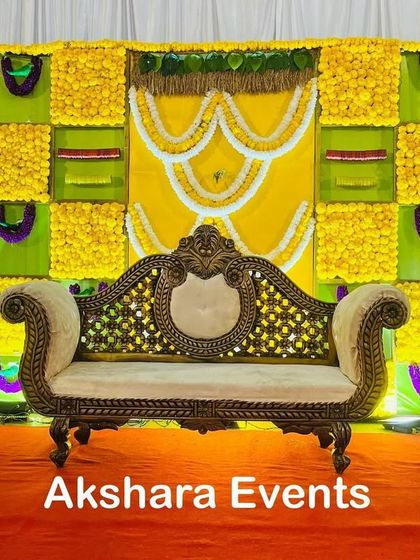 This Haldi-themed baby shower decor combines bright yellow marigolds with green fabric and intricate white floral patterns. The ornate sofa provides comfortable and regal seating for the main ceremony.