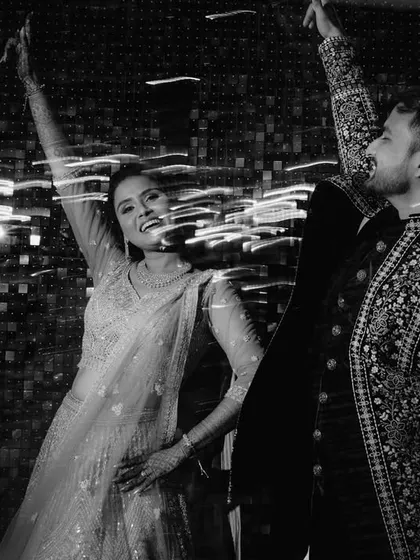 A black and white shot using a slow shutter speed to capture the couple's dance moves. The light trails create a sense of energy and movement against the sparkling backdrop.