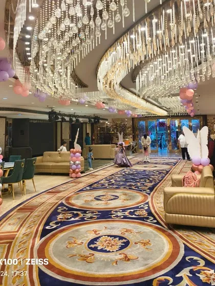 A wide shot of the banquet hall, showing how I used balloon bunches on the ceiling and themed pillars throughout the space to create an immersive butterfly garden feel.