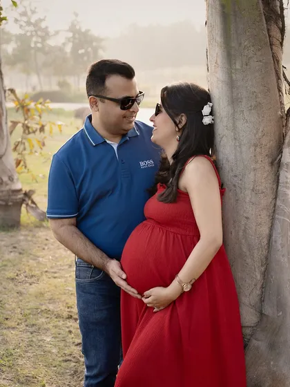 Lost in a moment together. Leaning against a tree, this couple shares a look of love and happiness. The golden hour sunlight filters through the trees, creating a warm and romantic atmosphere for their outdoor maternity shoot.