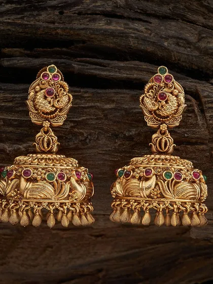 My collection is filled with classic jhumkas, and this pair is a customer favorite. These are traditional temple jhumkas with a detailed peacock stud, crafted in a rich antique gold tone and accented with ruby and emerald colored stones. They have a wonderful weight and swing, perfect for pairing with silk sarees.
