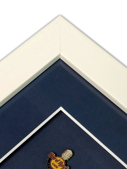 Another corner detail of the pin collection frame, showing the clean white frame and the double mat effect created by the inner white bevel on the blue mat. It's a small detail that makes a big difference.