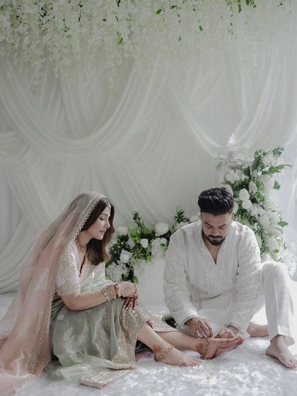 A tender moment between the couple, set against a backdrop of cascading white wisteria and soft drapery. The design is layered and textural, creating a visually rich yet calming environment.